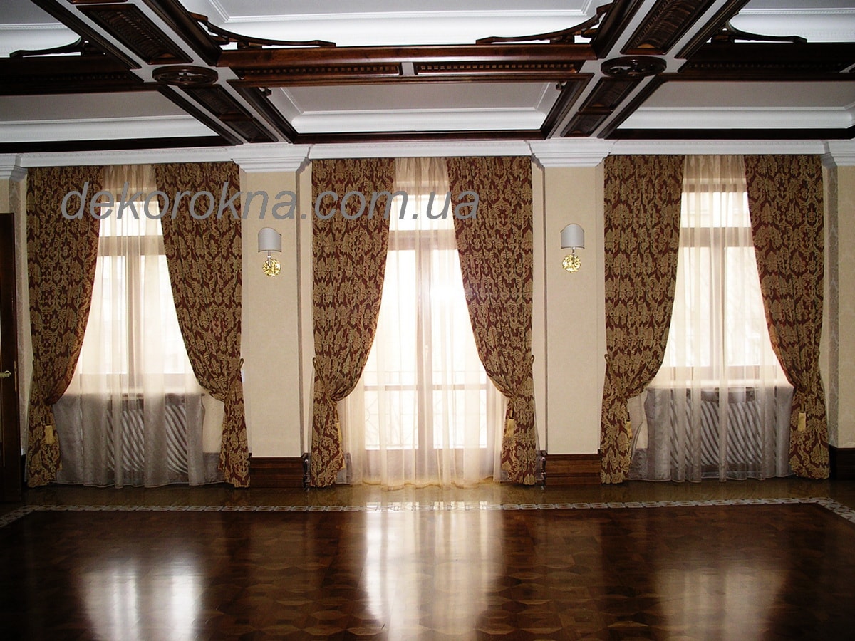 На шторах используется двухсторонняя бордово-золотая ткань с вензелем фирмы Kobe. Тонкая, прозрачныая гардина. Карнизы прячутся в нише.