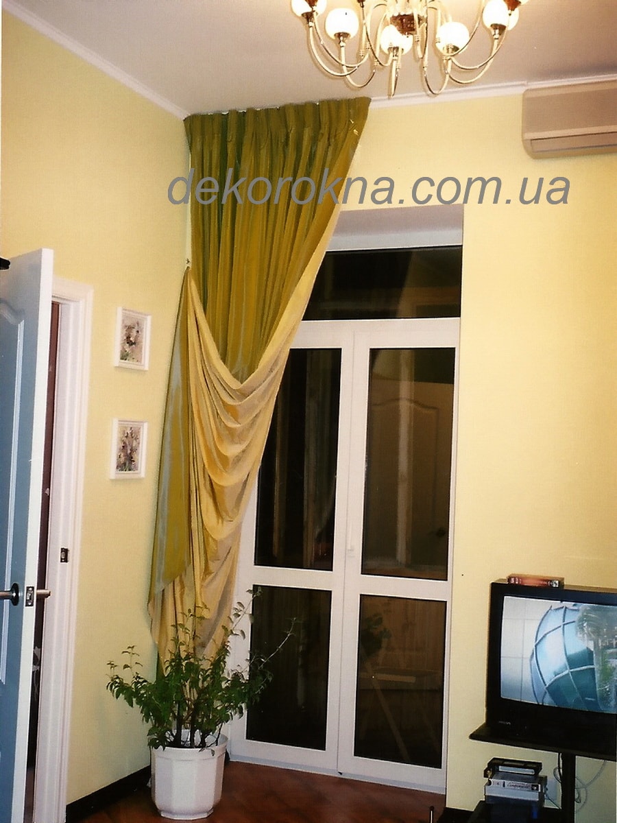 Ассиметричная штора в гостиную пошита из двух оттенков тафты зеленой и бежевой. Светлая ткань используется в качестве подкладки.