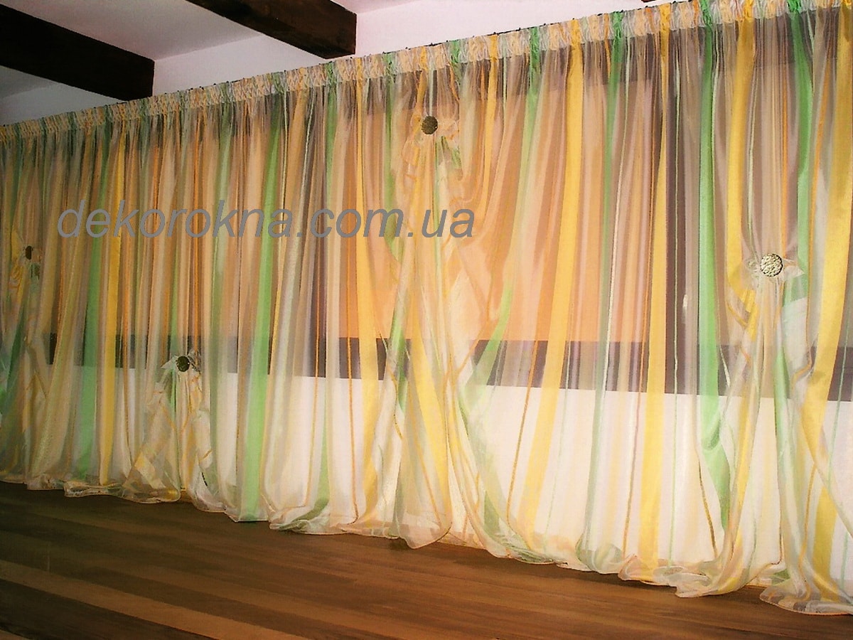 Для декора в гостиную используется тюль с желтой и салатовой вертикальной полосой. Магниты придают тюлю новый вид.